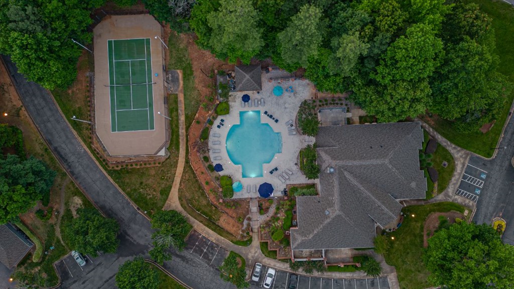 arial view of a swimming pool in the middle of a neighborhood with a house