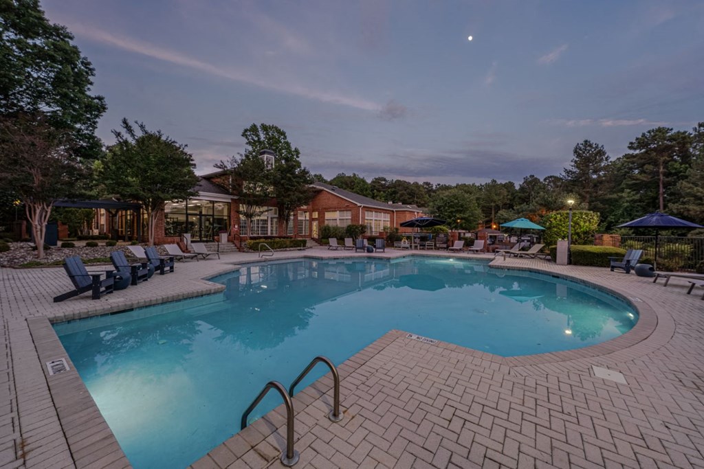 a swimming pool at night with chairs around it
