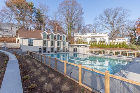 A pool surrounded by a wooden fence and a building in the background.