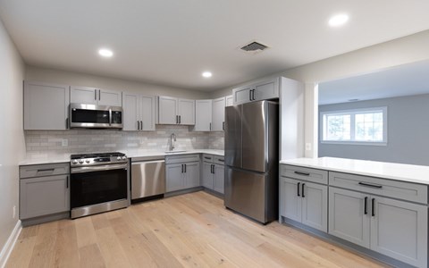 A modern kitchen with stainless steel appliances and wooden floors.