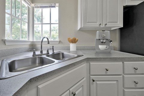 a white kitchen with a sink and a window