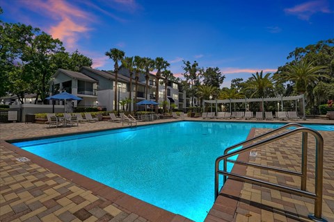 a resort style swimming pool with trees and buildings in the background