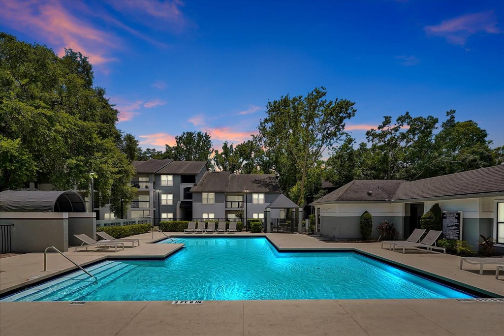 a swimming pool with trees and apartments in the background