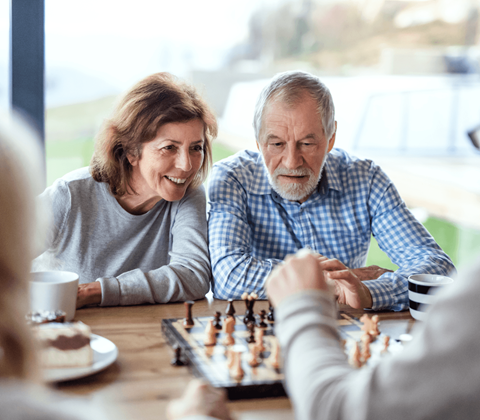 an older couple playing a game of chess on a table
