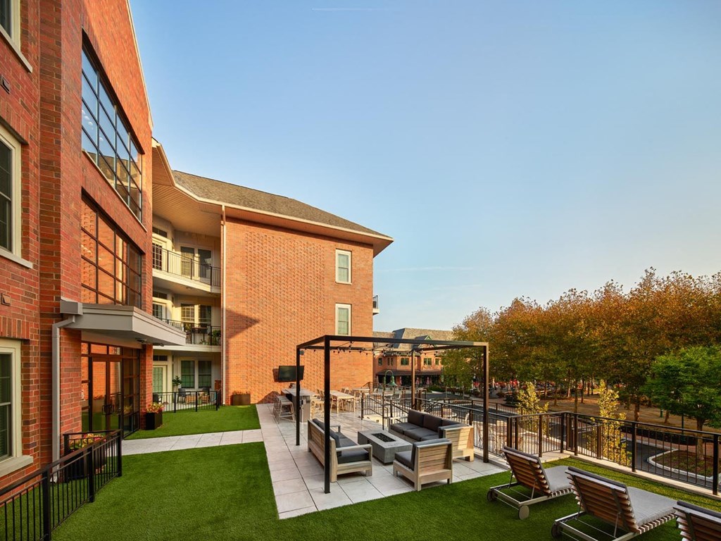 A modern outdoor seating area with a black metal pergola and wooden chairs.