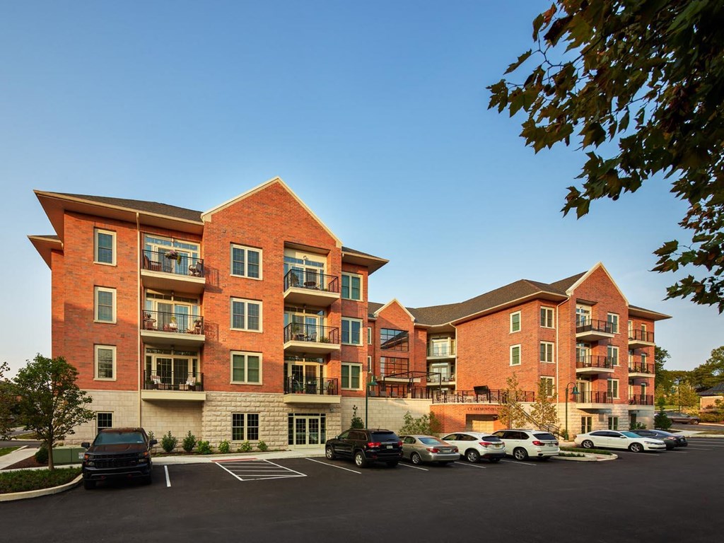 A large red brick apartment building with a parking lot in front.