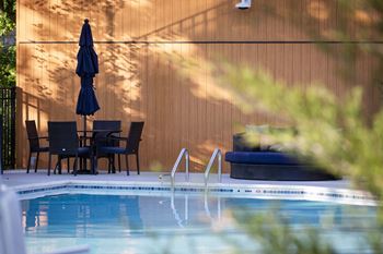 a swimming pool with chairs and an umbrella next to a pool