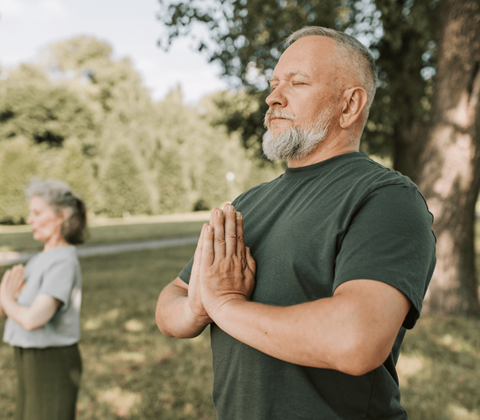 a man and a woman standing in a park with their hands together