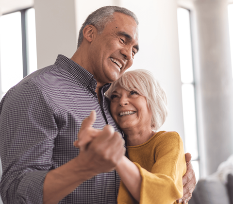 a man and a woman holding each other and smiling while dancing