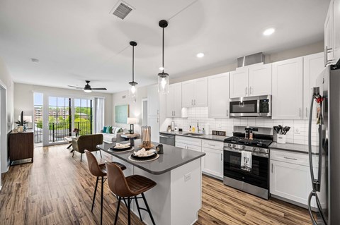 A modern kitchen with white cabinets and a wooden floor.