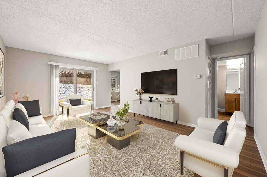 A living room with a white couch, a coffee table, and a television.