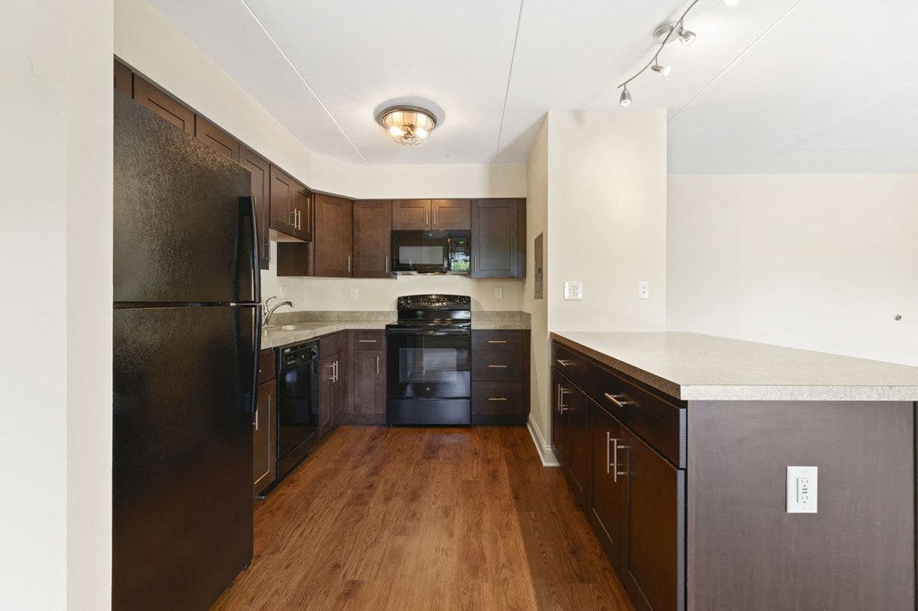 an empty kitchen with black appliances and wood floors