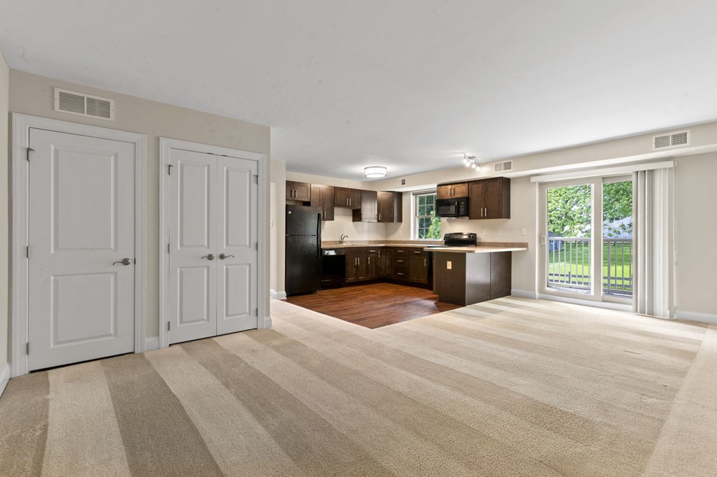 an empty living room and kitchen with a door to a balcony