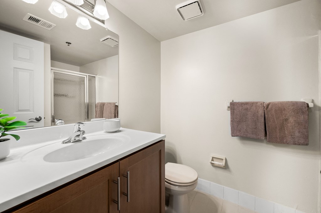 A bathroom with a toilet, sink, mirror, and towel rack.