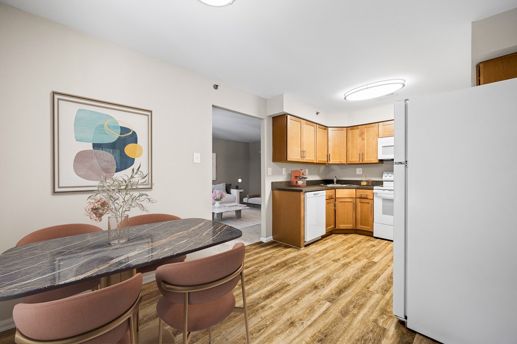 A kitchen with a table and chairs in the foreground and a refrigerator in the background.