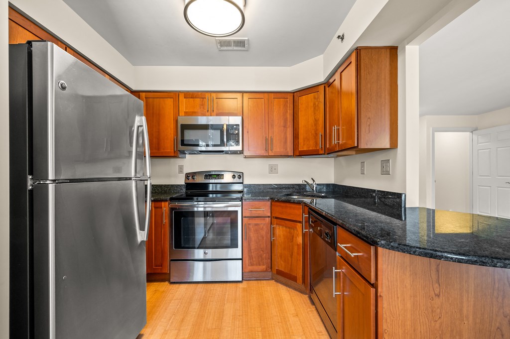 A kitchen with a black counter top and wooden cabinets.