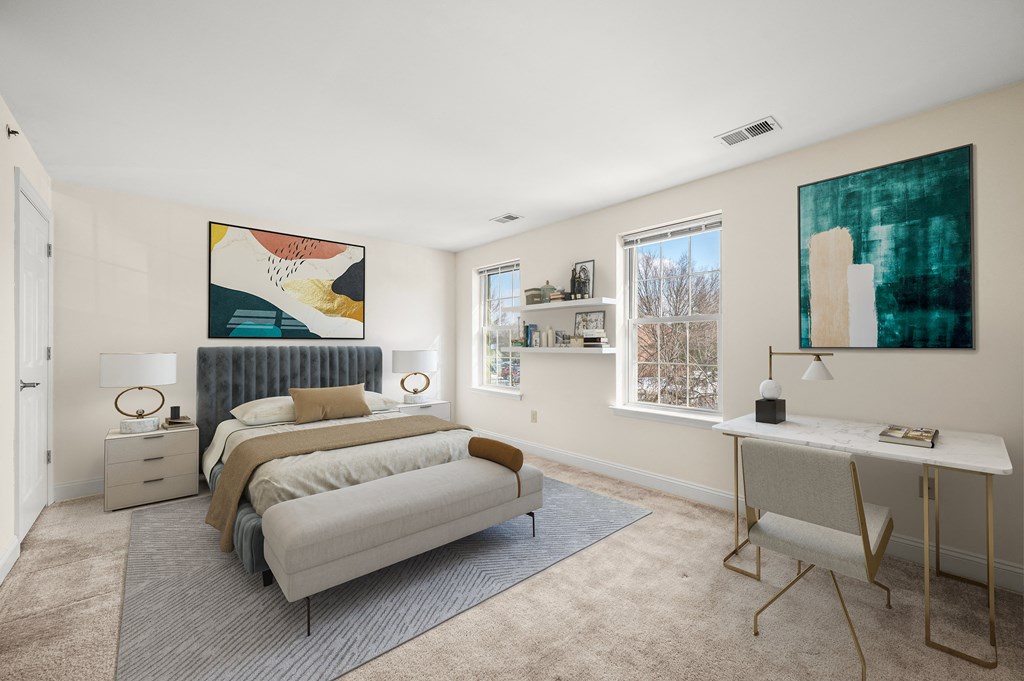 A bedroom with a bed, a desk, and a painting on the wall.