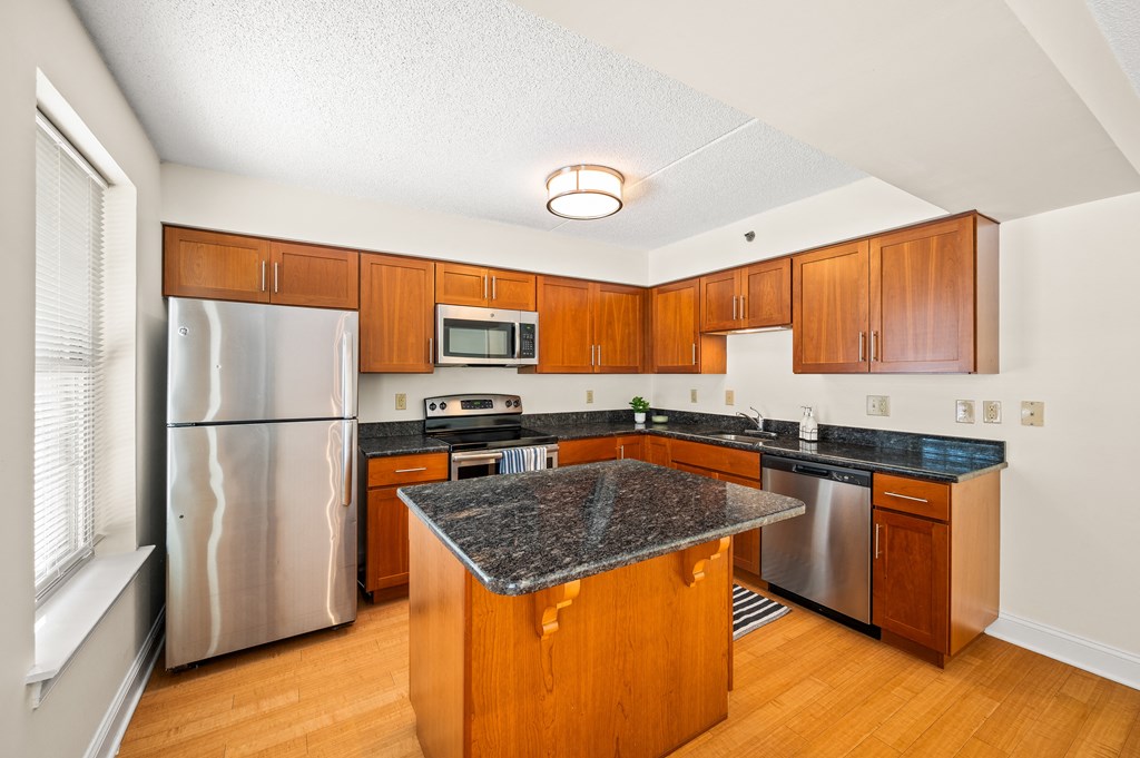 A kitchen with wooden cabinets and a granite counter top.