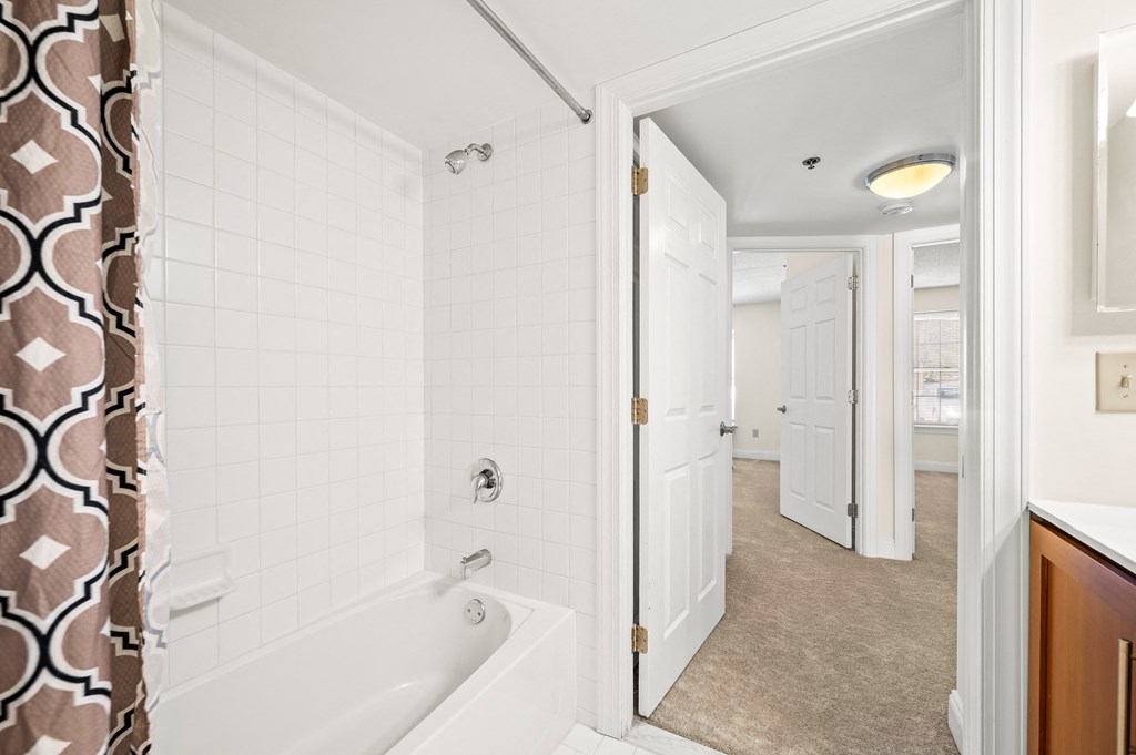 A bathroom with a white tub and a shower with a brown and white shower curtain.