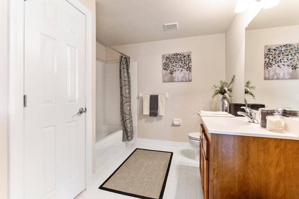 Clean and simple bathroom featuring a white door, toilet, sink, and a soft rug on the floor at Claremont Apartments in Exton, PA