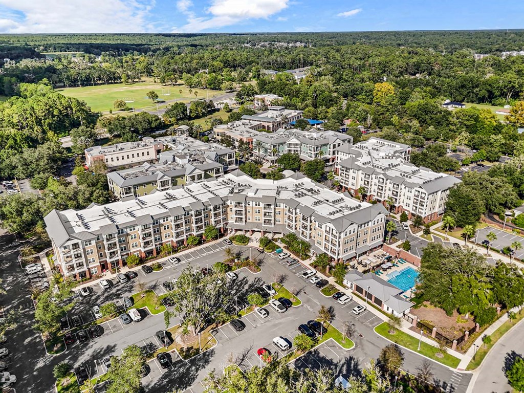 A large apartment complex with a swimming pool and surrounded by trees.
