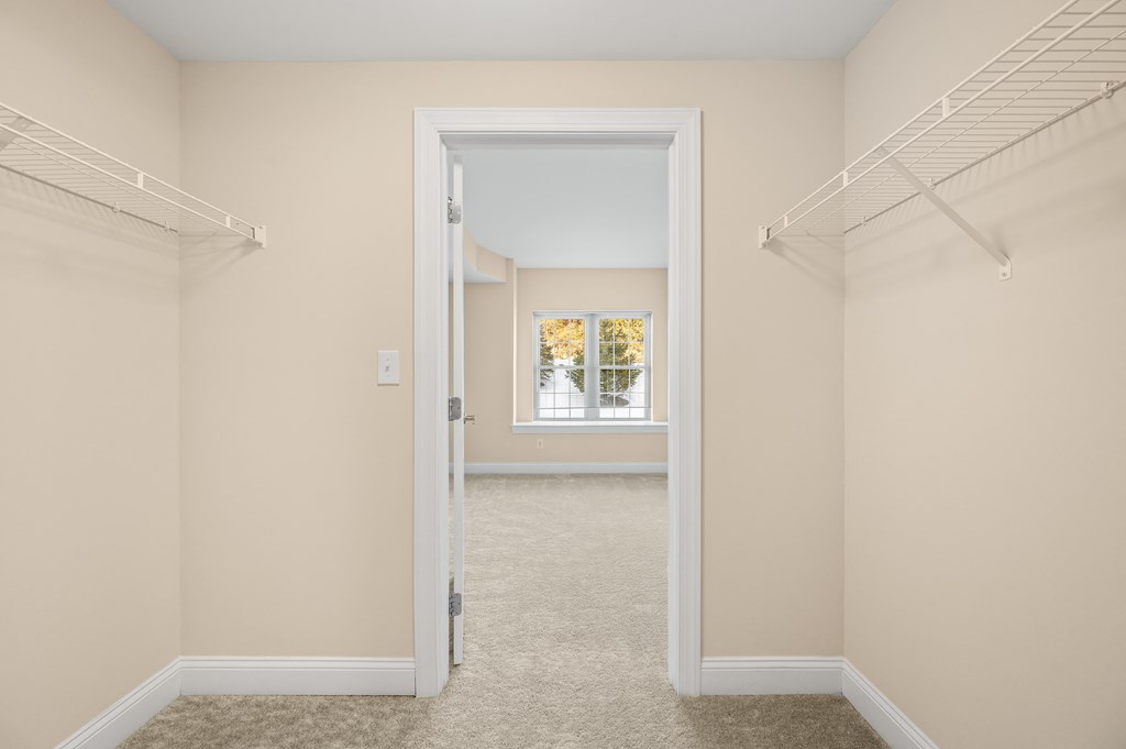 A room with a carpeted floor and a doorway leading to another room.