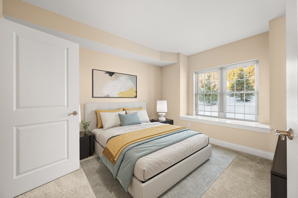 A bedroom with a bed, nightstand, and window.