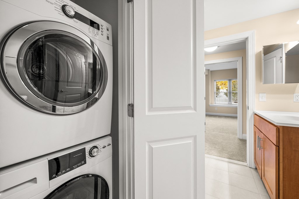 A washing machine is in the foreground of a modern laundry room.