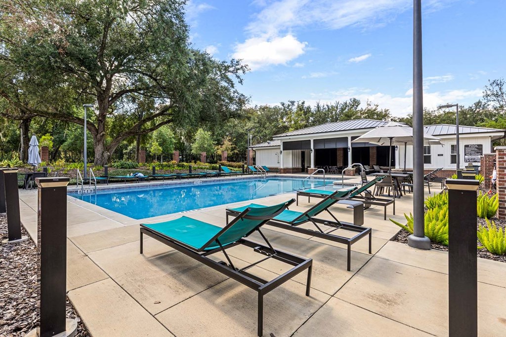 A pool with sun loungers and a building in the background.