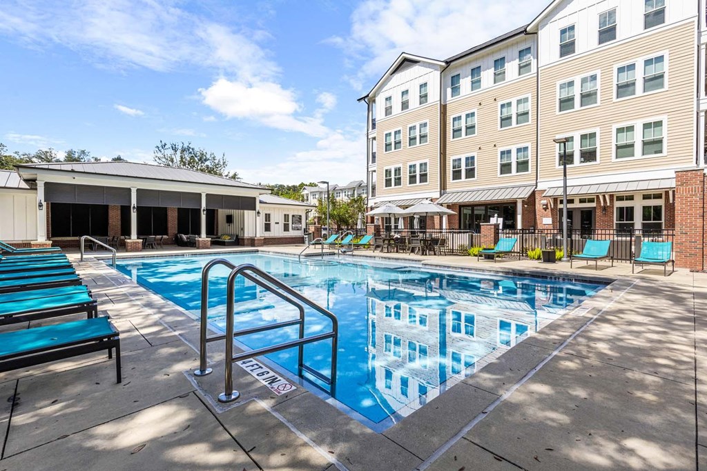 A pool with a diving board and a building in the background.
