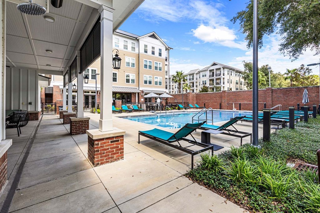 A pool area with a brick wall and a building in the background.
