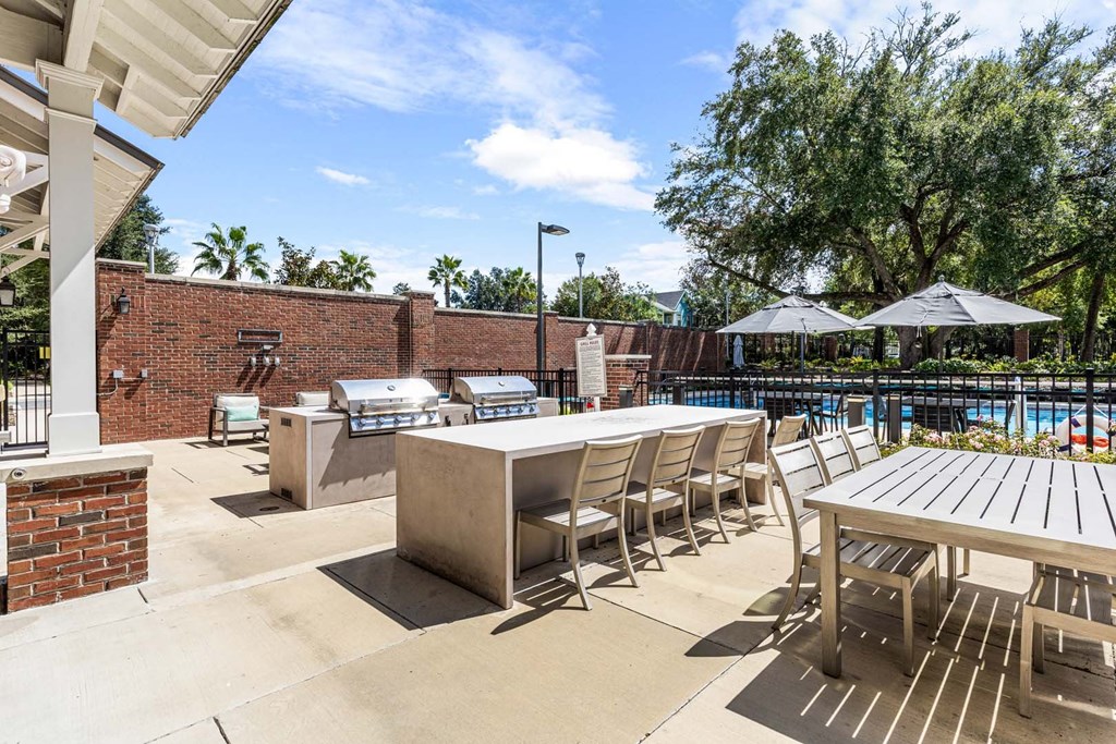 A poolside area with tables and chairs and a pool in the background.