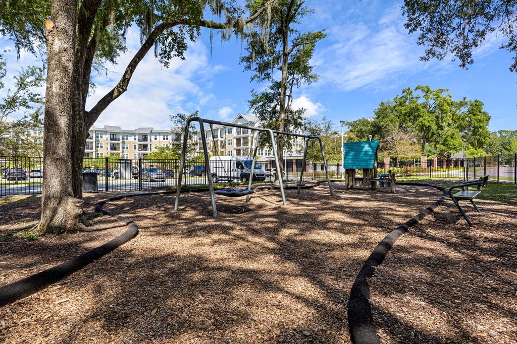 A playground with a swing set and a green canopy.