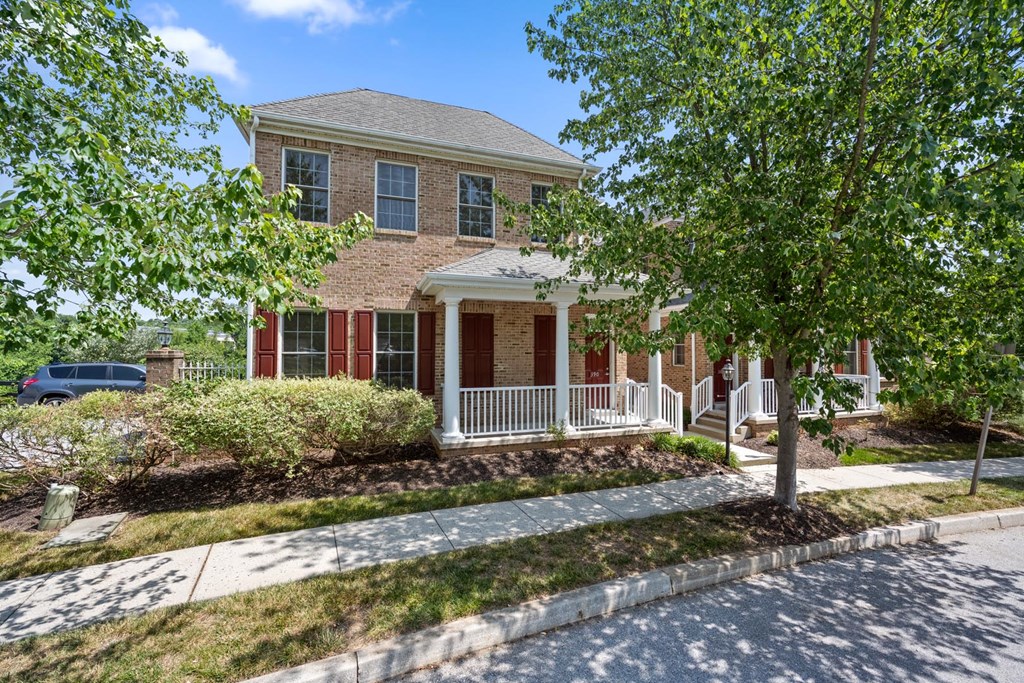Charming house with a red door and white trim, nestled amidst lush greenery at Claremont, Exton, PA