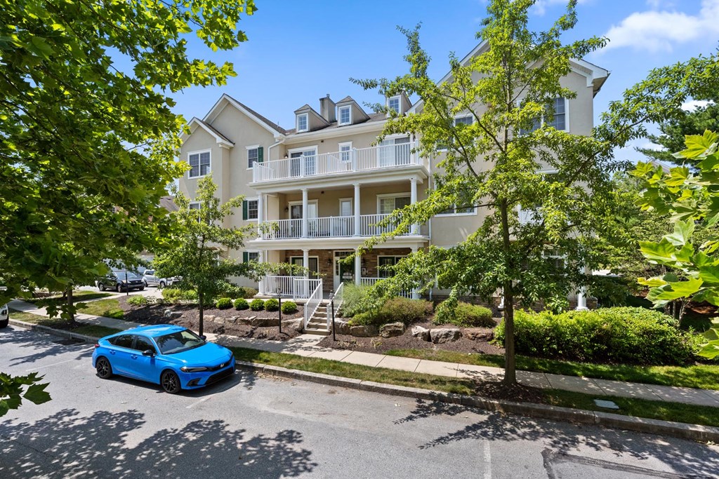 A blue car parked along the street in front of a white building at Claremont, Exton, PA