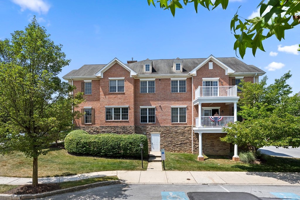 Charming red brick apartment building with a flag displayed on the balcony at Claremont Apartments in Exton, PA