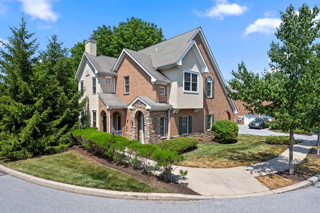 Spacious house featuring a grey roof and elegant stone pillar accents at Claremont, Exton, PA