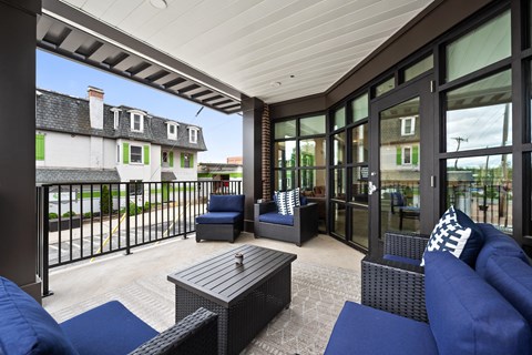 a covered patio with blue furniture and glass doors