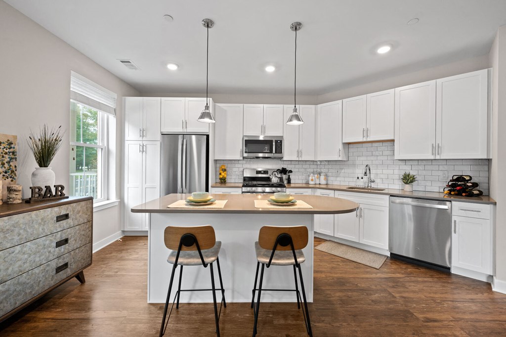 Modern kitchen with white cabinetry, a central island, and two stools at Hamilton at Eagleview in Exton, PA