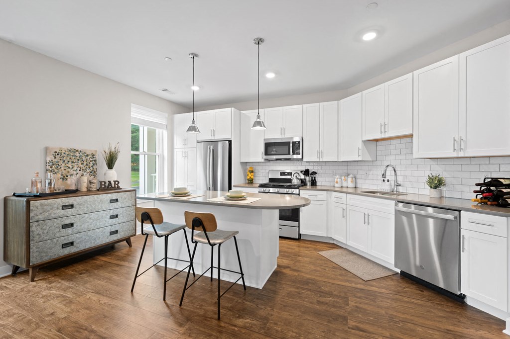 Modern kitchen with white cabinetry, a white island, and two stools at Hamilton at Eagleview in Exton, PA
