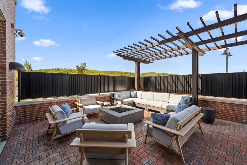 An outdoor patio with comfortable furniture, a fire pit, and a pergola.
