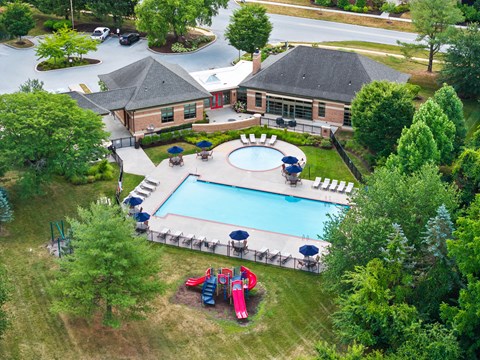 An aerial view of a pool surrounded by trees and a building.