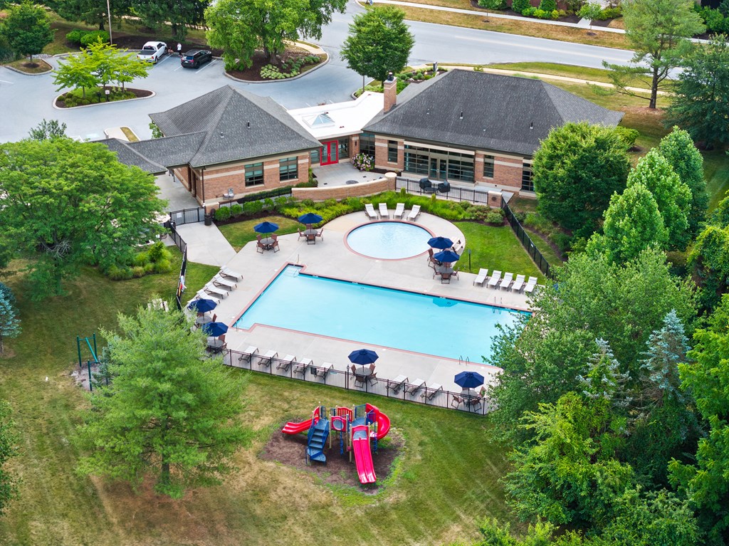 An aerial view of a pool surrounded by trees and a building.