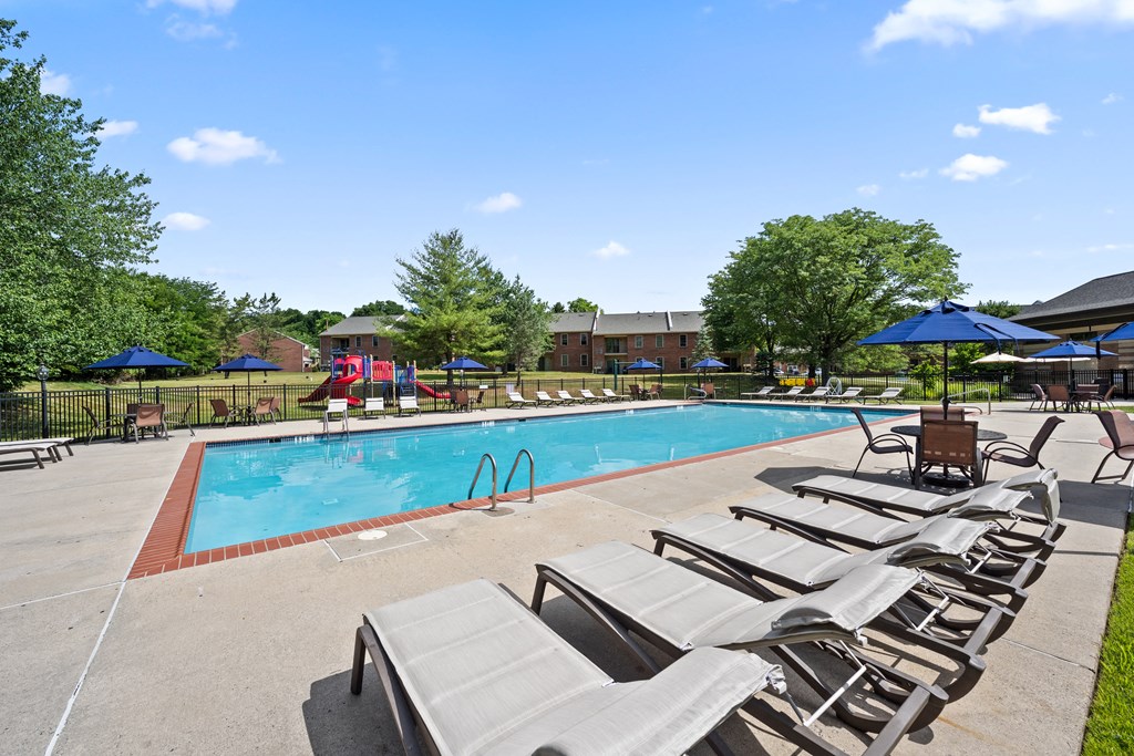 A pool with sun loungers and umbrellas in the foreground.