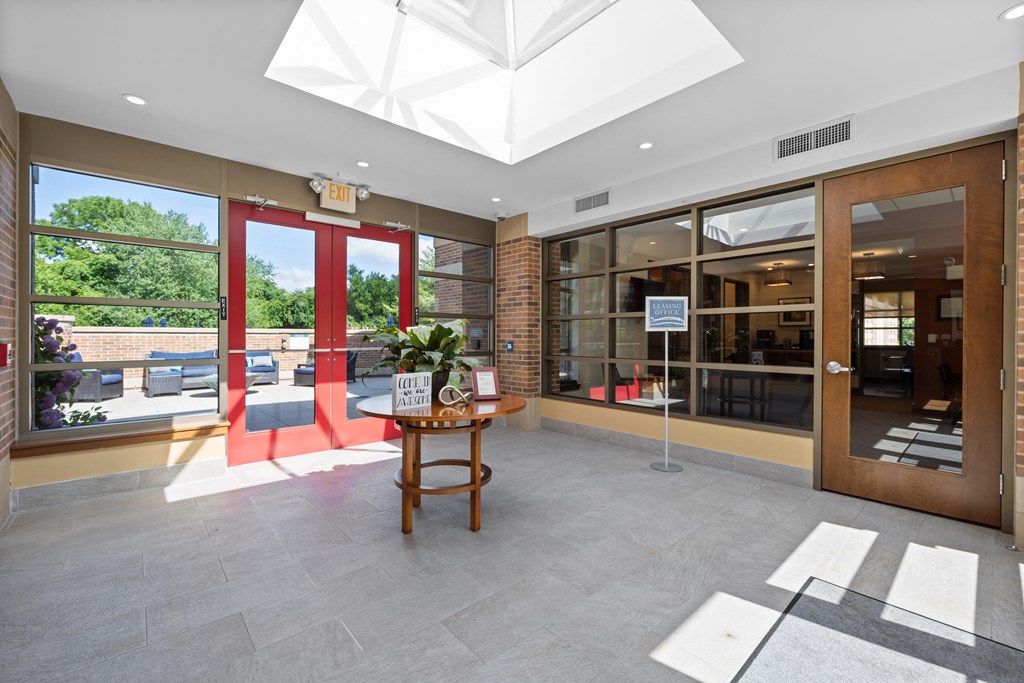 A brightly lit atrium with a skylight and a table with a plant on it.
