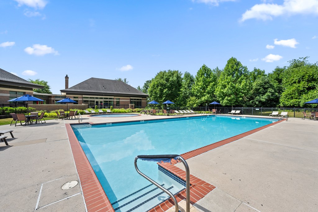 A pool surrounded by trees and a building in the background.
