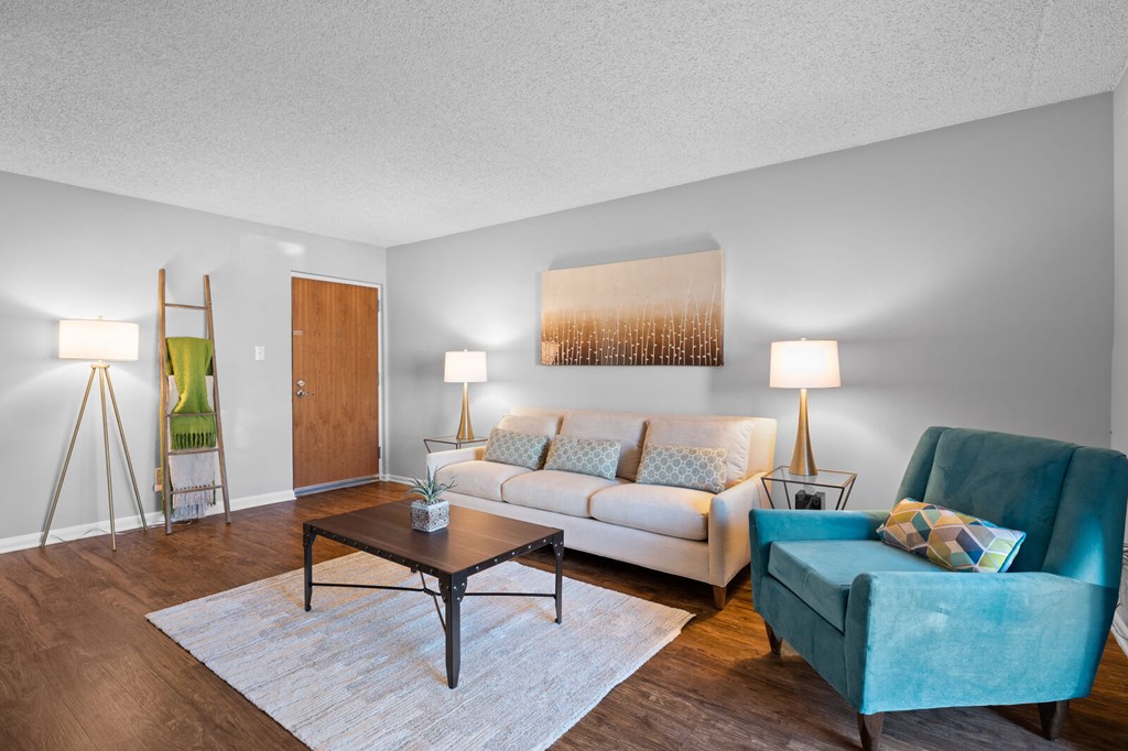 A large living room with hardwood-style flooring, an entry door, and ample natural light.