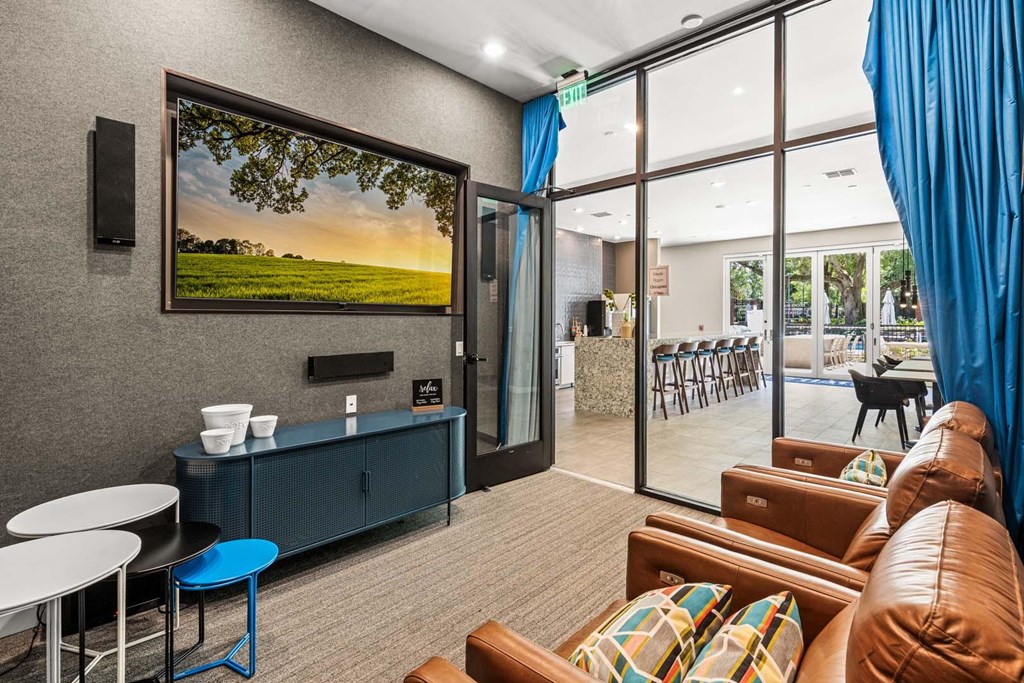 A living room with a large painting on the wall and a blue stool.