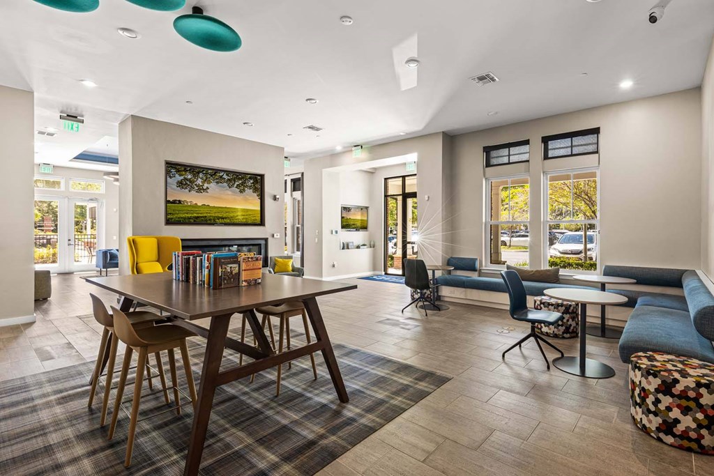 A room with a table and chairs in the foreground and a painting on the wall.