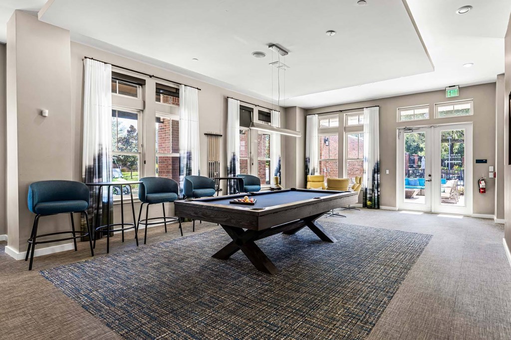 A room with a pool table and chairs.